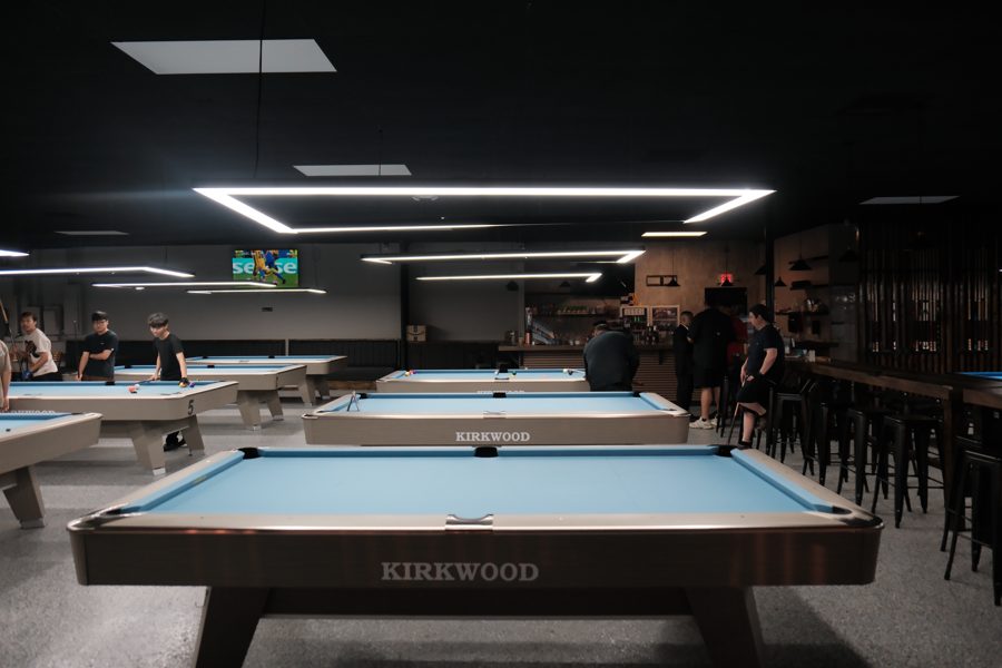 Player checking phone leaning on table 3 with the hall in the background