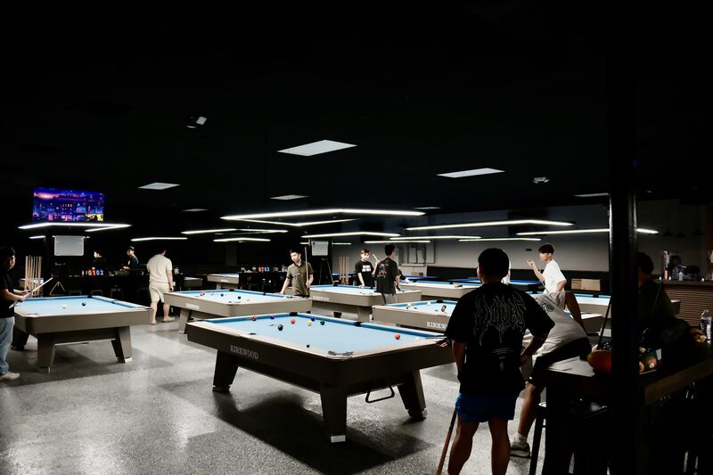 Players gathered around tables with live sports on the TVs